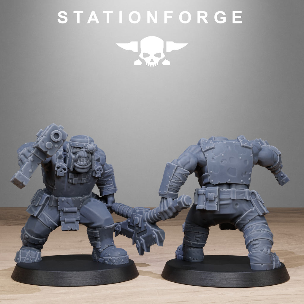 Two gray miniature figures on black bases with 'Stationforge' logo in the background